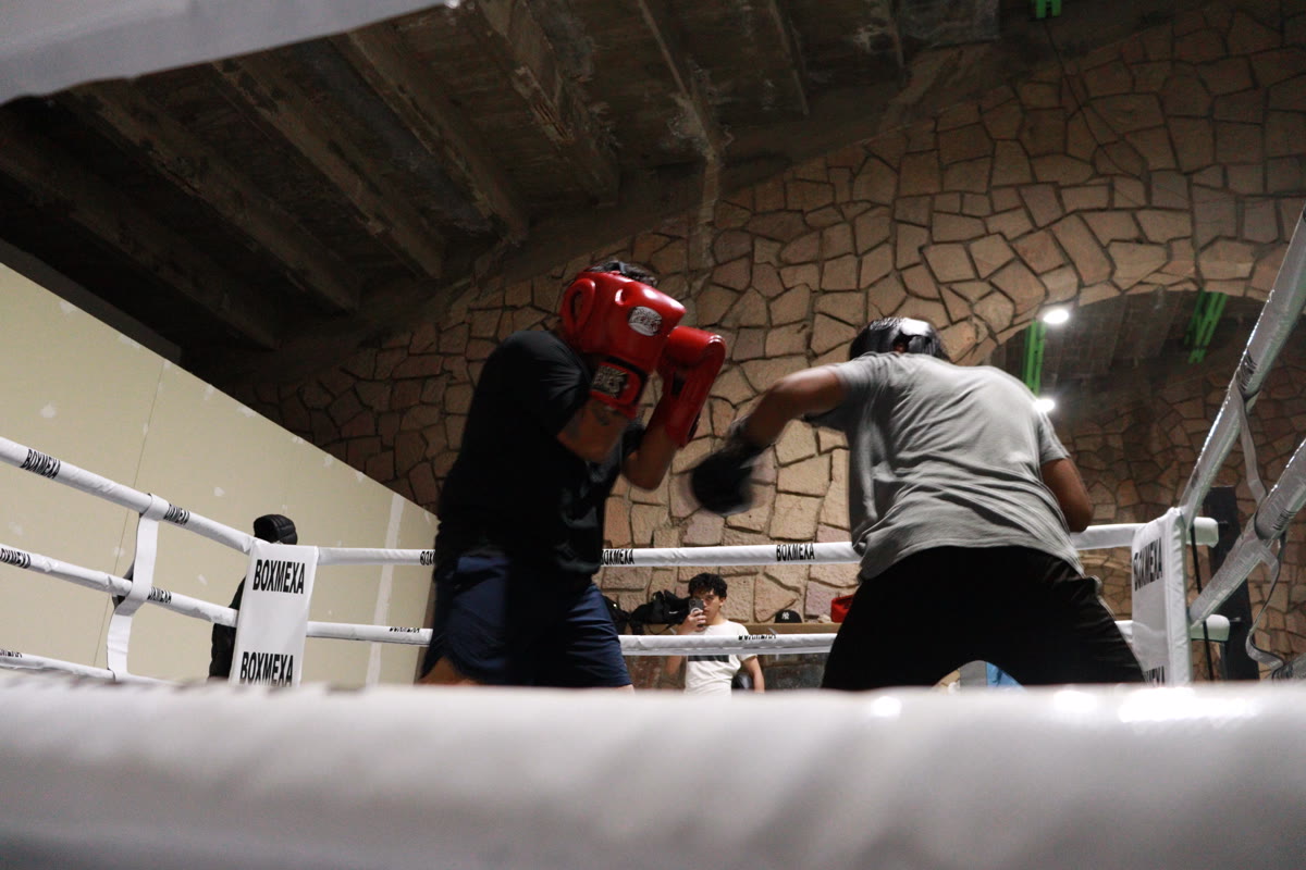 Dos personas hacen sparring en el ring, vistas desde un ángulo bajo.